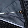 A close-up view of a gas strut mechanism attached to a black polyrattan storage box, with a gray cushion visible inside. Produktbild-Vorschau