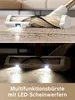 Close-up of a vacuum cleaner brush head with LED lights illuminating dirt on a carpet and floor. Produktbild-Vorschau
