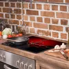 A kitchen counter with a stovetop, cooking utensils, and ingredients. Anteprima dell’immagine prodotto