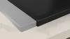A close-up view of the corner of a black induction cooktop with a silver trim, resting on a light-colored countertop. Voir les images du produit