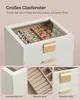 A close-up view of a white jewelry box with a glass lid, showcasing its interior compartments filled with jewelry. The image is divided into three smaller inset images at the bottom, highlighting specific features. Produktbild-Vorschau