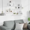 A living room scene with a sofa and shelves on the wall. Voir les images du produit