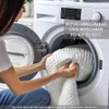 A person is putting a white quilted item into a washing machine. Produktbild-Vorschau