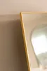 A close-up shot of the corner of a gold-framed mirror leaning against a wall. Náhled obrázku produktu
