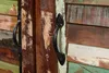 A close-up view of two black handles on a rustic wooden cabinet. Náhled obrázku produktu