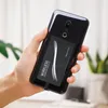 A hand holds a smartphone with a wireless charging receiver attached to the back. Produktbild-Vorschau