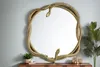 A decorative mirror with a gold snake sculpture frame, placed on a wooden dresser with a plant and decorative bottles. Produktbild-Vorschau
