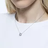 A close-up shot of a person wearing a silver necklace with a square pendant. Produktbild-Vorschau