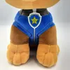 Close-up view of the lower body of a plush toy dog, showing its blue uniform with a badge. Voir les images du produit