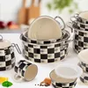 A collection of cookware with a black and white checkered pattern, arranged on a white surface with some kitchen ingredients in the foreground. Voir les images du produit