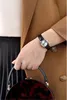 A close-up shot of a woman's wrist wearing a watch and holding a handbag. Anteprima dell’immagine prodotto