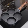 A square-shaped frying pan with four circular molds and a wooden handle sits on a black stovetop. Náhľad obrázku produktu