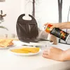 A person is spraying a sandwich maker with cooking spray. Produktbild-Vorschau