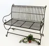 A metal garden bench on a white background with a small potted plant next to it. Produktbild-Vorschau