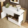 A modern sideboard with high-gloss white drawers and doors, contrasted with a wood grain finish. The sideboard is open, revealing storage compartments and drawers with some items inside. A lamp and a small floral arrangement are placed on top. Voir les images du produit