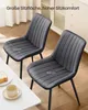 Two gray dining chairs are shown in a room setting with a table and a cabinet in the background. Produktbild-Vorschau