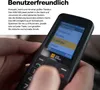 A person's hands are holding a black AGM Mobile M9 phone, showing its screen and keypad. Podgląd zdjęcia produktu