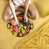 A person sitting on a yellow bed with a tray of fruit. Náhľad obrázku produktu