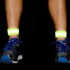 Close-up of a person's legs wearing running shoes and reflective ankle bands. Náhled obrázku produktu