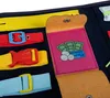 A close-up view of a busy board for toddlers, showing various fasteners and a small wallet with money and a card. Produktbild-Vorschau