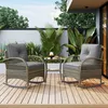 A patio set with two rocking chairs and a small table on a wooden deck, surrounded by lush greenery. Produktbild-Vorschau