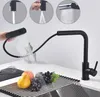 A black kitchen faucet with a pull-down sprayer is shown in use, demonstrating its different spray modes. Fruits and a whisk are placed on a drying rack in the foreground. Náhled obrázku produktu