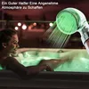 A woman relaxing in a hot tub with a shower head emitting green light and water. Produktbild-Vorschau