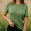 A woman wearing a green knitted top stands in a field of grass. Produktbild-Vorschau
