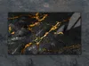 A rectangular glass cutting board with a black marble pattern and gold veins, placed on a dark textured surface. Náhľad obrázku produktu