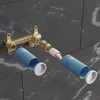 An exploded view of a shower valve installation kit, showing the brass valve body, cartridge, and protective sleeves against a tiled wall. Produktbild-Vorschau