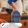 A child is shown from the waist down, wearing plaid pajama bottoms and pulling up a white t-shirt. Podgląd zdjęcia produktu