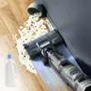 A vacuum cleaner is shown cleaning a spill on a wooden floor. Voir les images du produit