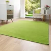A living room with a green rug, a white armchair, and a chest of drawers.