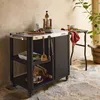 An outdoor serving cart with kitchen utensils and ingredients set up on a stone patio. Produktbild-Vorschau