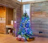 A decorated Christmas tree with presents underneath in a room with wooden walls. Produktbild-Vorschau