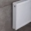 A white radiator is mounted on a gray tiled wall. Produktbild-Vorschau