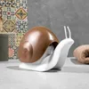 A snail-shaped soap dispenser sits on a countertop in a bathroom. Voir les images du produit