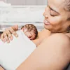 A mother is holding her newborn baby close to her chest. Produktbild-Vorschau