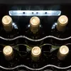 A close-up view of the tops of several wine bottles stored in a wine cooler, illuminated by LED lights. Produktbild-Vorschau