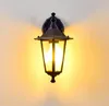 A black outdoor wall light fixture with glass panels, mounted on a wall. Produktbild-Vorschau