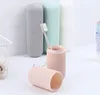 Several toothbrush holders in different pastel colors are displayed on a white surface, with one pink holder open and a toothbrush inside. Produktbild-Vorschau
