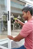 A man is using a cordless drill to work on a sliding glass door handle. Voir les images du produit