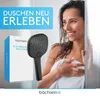 A woman wrapped in a towel is smiling in a bathroom setting, with a showerhead and its packaging displayed prominently. Produktbild-Vorschau