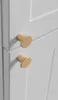 A close-up shot of two gold cabinet knobs on a white cabinet door. Podgląd zdjęcia produktu