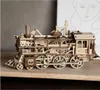 A wooden model of a steam locomotive sits on a wooden surface, with a sketch of a face in the background. Náhľad obrázku produktu