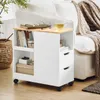 A white rolling cabinet with a wood-tone top sits next to a couch with a knitted blanket. Náhľad obrázku produktu