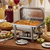 A chafing dish filled with food, set up on a table with other dishes, suggesting a buffet or catering setup. Podgląd zdjęcia produktu