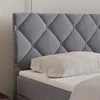 A close-up view of a gray upholstered headboard and mattress with a white pillow. Produktbild-Vorschau