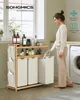A woman is sorting laundry next to a SONGMICS bamboo laundry basket with three compartments. Produktbild-Vorschau