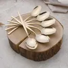 A set of champagne-colored spoons arranged on a wooden block. Anteprima dell’immagine prodotto